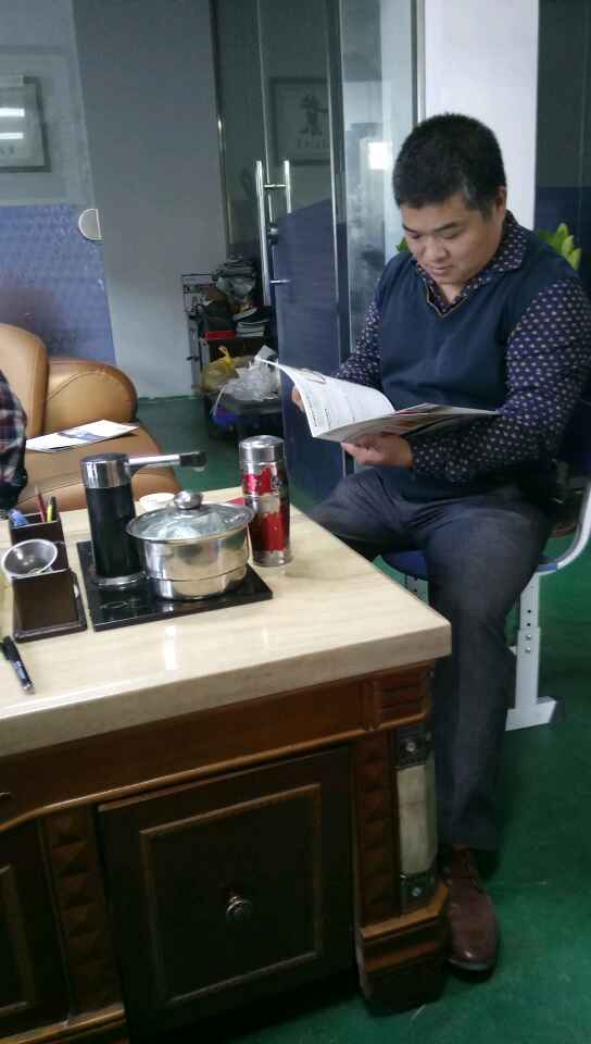 南海陳祥明老板想買凱恩利46車先銑機——在邊聽業(yè)務代表講解產品特點優(yōu)點邊看宣傳書。